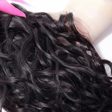 Black curly hair extensions held by a person with a pink hair clip, brand 'ISEE' visible.